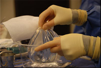 doctor holding breast implant performing breast augmentation procedure